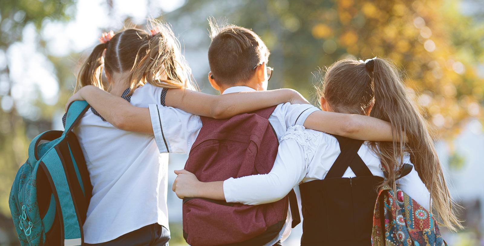 Children with backpacks walking together, representing family life and schools